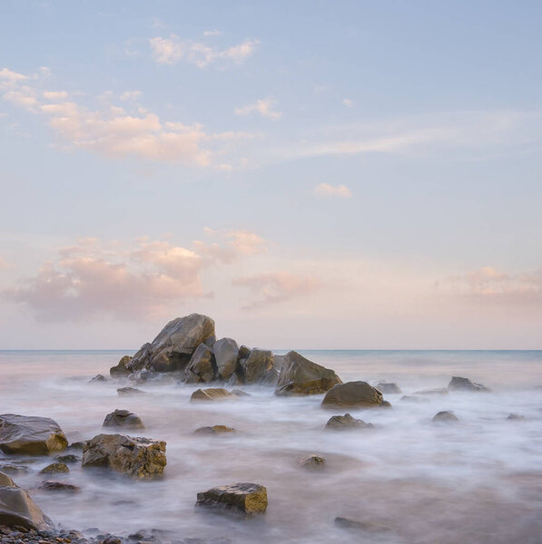 heap of huge stones near a calm sea coast at the sunset