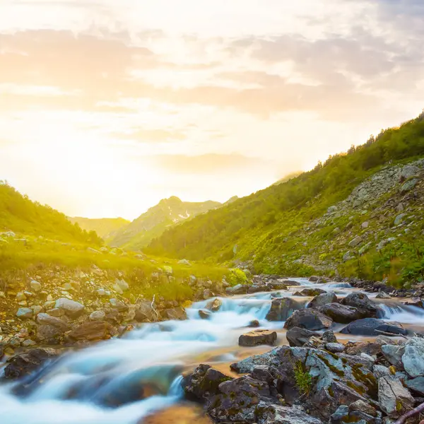 Dağ nehri gün batımında taşların üzerinden akıyor. Akşam dağları manzarası.