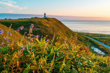 Gün batımında deniz kıyısı boyunca tepenin üstündeki deniz feneri. Nevelsk, Sakhalin Adası, Rusya