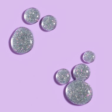 Oje, gümüş parlatıcı jel, mor arkaplana düşer.