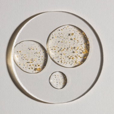 Beyaz zemin üzerinde altın olan bir damla serum, kozmetik dokular, cilt ürünü lekesi yüz serumu, yağ