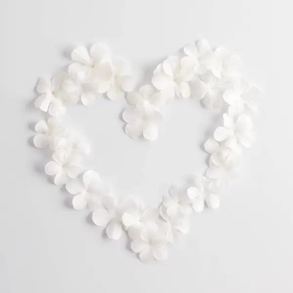 Beyaz çiçeklerin kalp şekli beyaz arka planda, tebrik kartı için tasarlanmış.