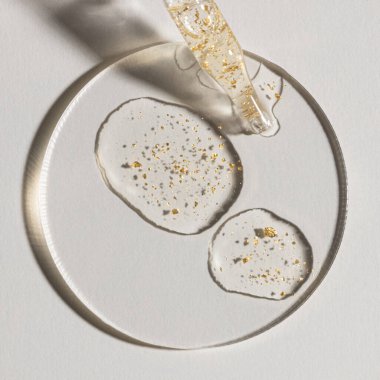 Beyaz zemin üzerinde altın olan bir damla serum, kozmetik dokular, cilt ürünü lekesi yüz serumu, yağ