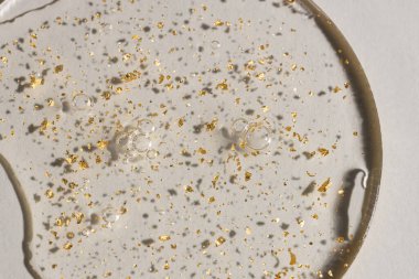 Beyaz zemin üzerinde altın olan bir damla serum, kozmetik dokular, cilt ürünü lekesi yüz serumu, yağ