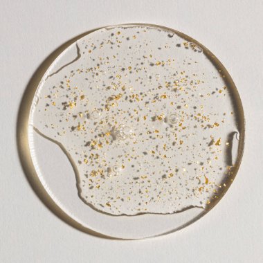 Beyaz zemin üzerinde altın olan bir damla serum, kozmetik dokular, cilt ürünü lekesi yüz serumu, yağ