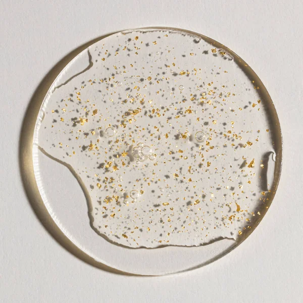 Beyaz zemin üzerinde altın olan bir damla serum, kozmetik dokular, cilt ürünü lekesi yüz serumu, yağ