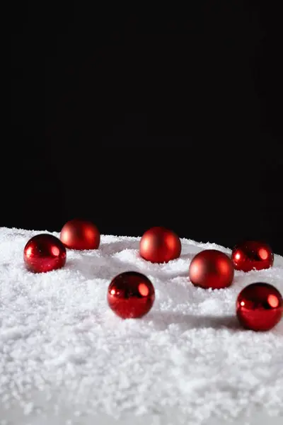 Noel, yeni yıl afişi, karlı süsleme, karda duran kırmızı Noel ağacı topları.