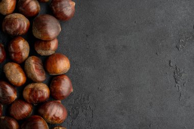 Raw  roasted chestnuts on black background