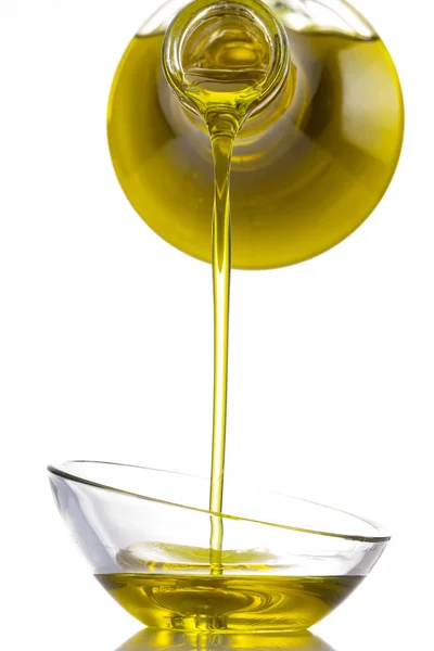 stock image Organic olive oil pouring from carafe  into glass bowl