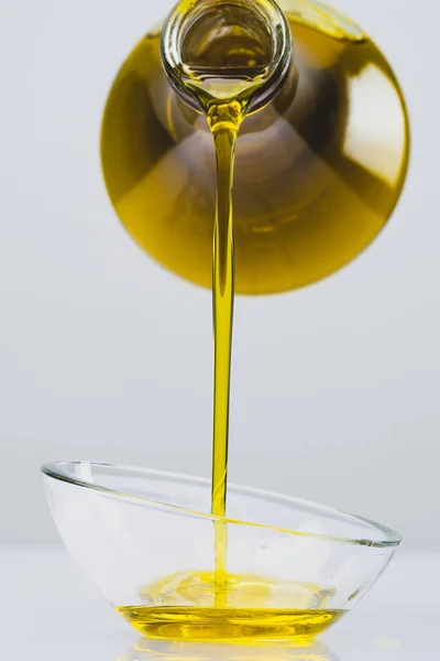 stock image Organic olive oil pouring from carafe  into glass bowl