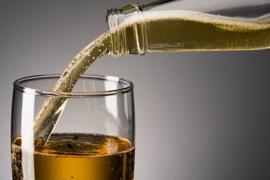 Koyu arkaplanda köpük olan bir bardak bira.