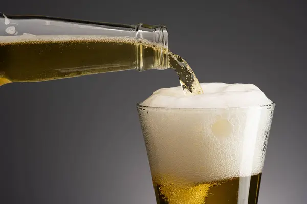 Glass of beer with foam on dark background