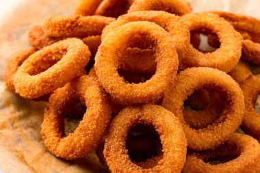  Kızarmış soğan halkaları, mozarella ya da sade. Masada lezzetli soğan halkaları var.