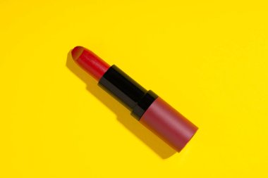 Sarı arka planda kırmızı ruj. Ruj kadınlar için vazgeçilmez bir makyaj ürünüdür.