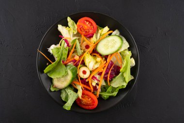 Sağlıklı beslenmek için siyah arka planda taze salata.