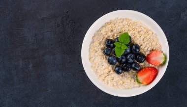 Kahvaltı için yaban mersinli, çilekli sütlü yulaf lapası.