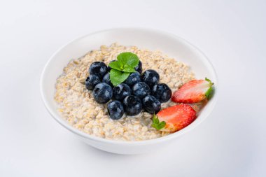 Kahvaltı için yaban mersinli, çilekli sütlü yulaf lapası.