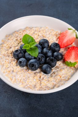 Kahvaltı için yaban mersinli, çilekli sütlü yulaf lapası.