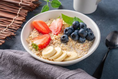 Kahvaltı için yaban mersinli, çilekli ve muzlu sütlü lapa.