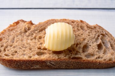 Yemeklere tat katan ve kahvaltıda beyaz ahşap arka planda olan tereyağı.