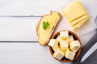 Yemeklere tat katan ve kahvaltıda beyaz ahşap arka planda olan tereyağı.