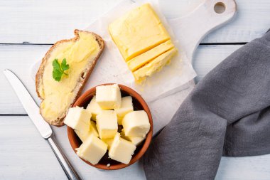 Yemeklere tat katan ve kahvaltıda beyaz ahşap arka planda olan tereyağı.