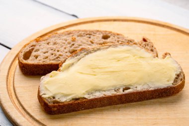 Yemeklere tat katan ve kahvaltıda beyaz ahşap arka planda olan tereyağı.