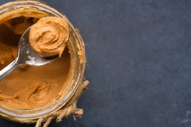 Siyah arka planda lezzetli ve sağlıklı fıstık ezmesi.