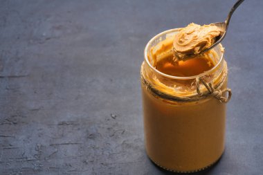 Siyah arka planda lezzetli ve sağlıklı fıstık ezmesi.