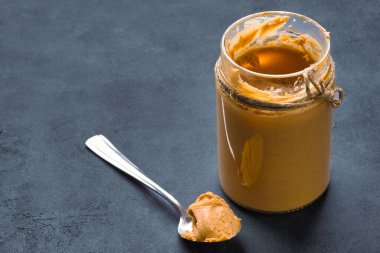 Siyah arka planda lezzetli ve sağlıklı fıstık ezmesi.