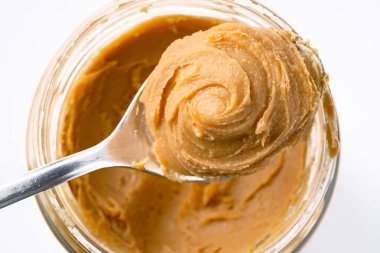 Beyaz arka planda lezzetli ve sağlıklı fıstık ezmesi.