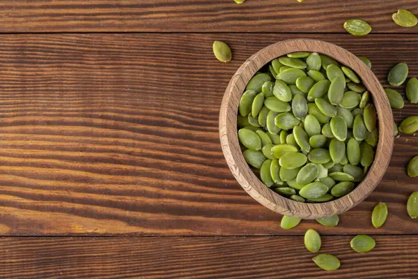 Ahşap arka planda lezzetli kabak tohumları