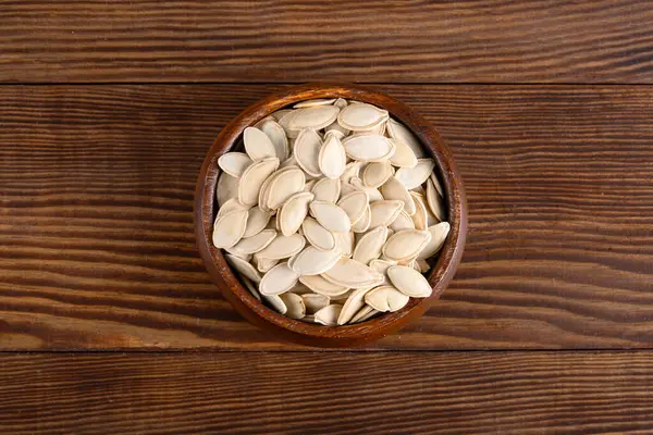 Ahşap arka planda lezzetli kabak tohumları