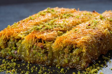 Lezzetli Türk fıstıklı kadayif tatlısı. Siyah arkaplanda Burma kadayif