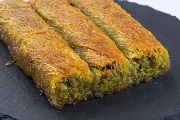 Lezzetli Türk fıstıklı kadayif tatlısı. Siyah arkaplanda Burma kadayif