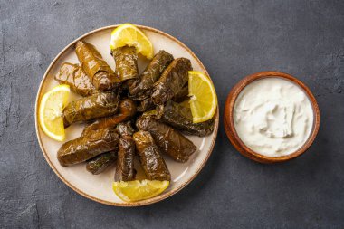 Lezzetli Türk yemekleri, sarmaşık yaprakları, siyah taş bir masanın üzerinde.