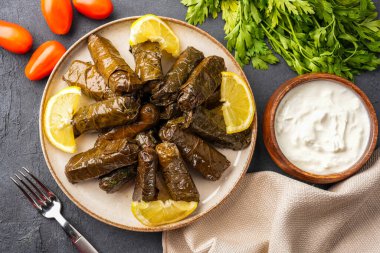 Lezzetli Türk yemekleri, sarmaşık yaprakları, siyah taş bir masanın üzerinde.