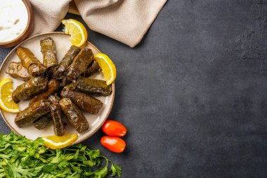 Lezzetli Türk yemekleri, sarmaşık yaprakları, siyah taş bir masanın üzerinde.
