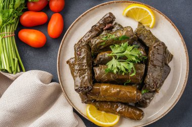 Lezzetli Türk yemekleri, sarmaşık yaprakları, siyah taş bir masanın üzerinde.