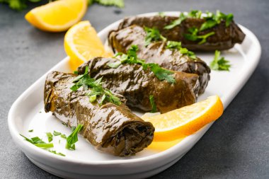 Lezzetli Türk yemekleri, sarmaşık yaprakları, siyah taş bir masanın üzerinde.