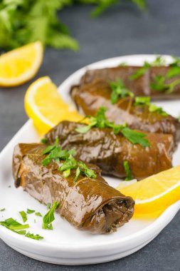 Lezzetli Türk yemekleri, sarmaşık yaprakları, siyah taş bir masanın üzerinde.