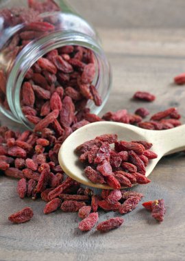Tahta kaşıkta goji üzümü. Cam bir kavanozda kurutulmuş goji.