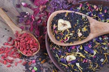 Tahta kaşıkta goji üzümü ve kasede çeşitli çay. Çiçek yaprakları ve kurt üzümü ile karıştırılmış çay. en üstteki görünüm