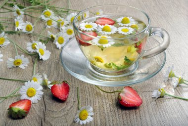 papatya ve çilek çayı üzerinde ahşap bir masa. vitaminler bitkisel çay.