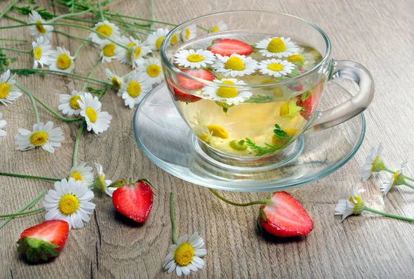 chamomile and strawberry tea on a wooden table. vitamins herbal tea.
