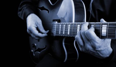 Gitarist elleri ve gitarist elleri yakın çekim. Elektro gitarı mavi tonda çalmak