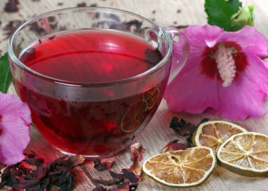 Cam bardakta Hibiscus çayı ve ahşap masada kurutulmuş limon dilimleri. Hibiscus çiçeği. Soğuk algınlığı ve grip için vitamin çayı.
