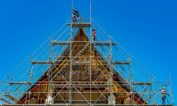 Construction work crews are building up a temporary structure over a temple needing repair.