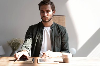 İş yerindeki genç çalışan cep telefonu kullanıyor, akıllı telefondan sosyal medyayı kontrol ediyor, ara veriyor, boşluk kopyalıyor