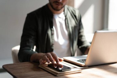 İş yerindeki genç çalışan cep telefonu kullanıyor, akıllı telefondan sosyal medyayı kontrol ediyor, ara veriyor, boşluk kopyalıyor